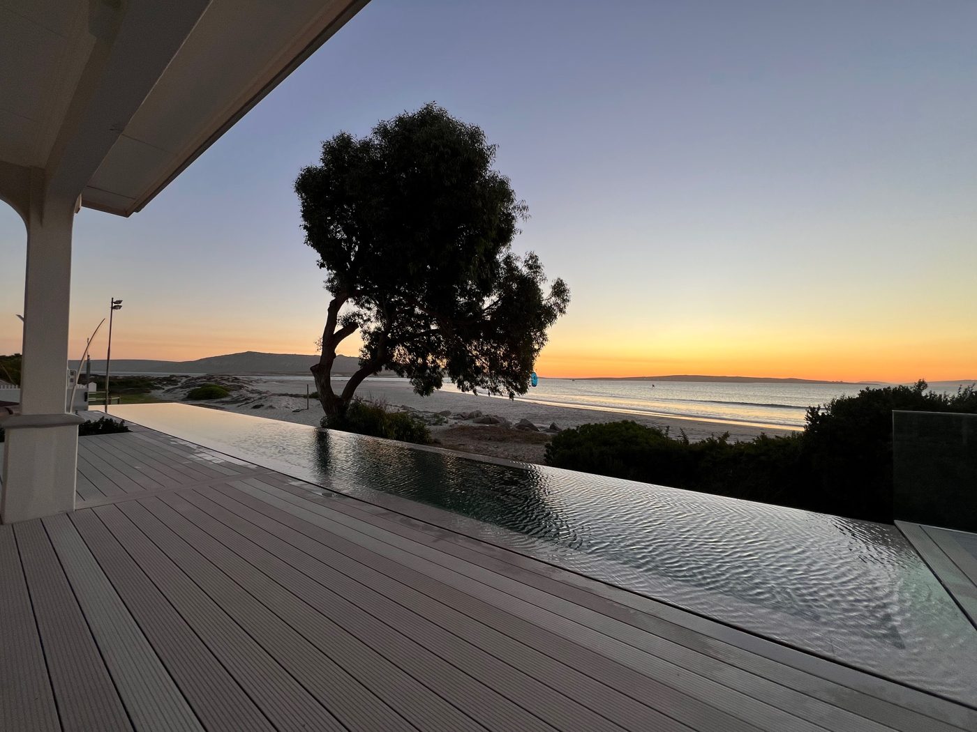 Terrasse und Infinity-Pool bei Sonnenuntergang mit Blick auf die Lagune