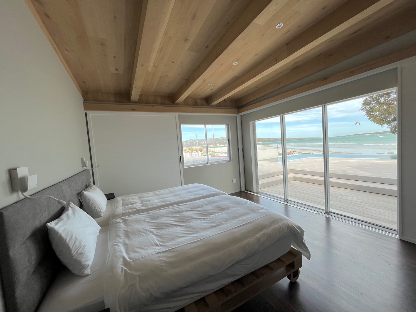 Helles Schlafzimmer mit grosser Schiebetür und Blick auf den Strand