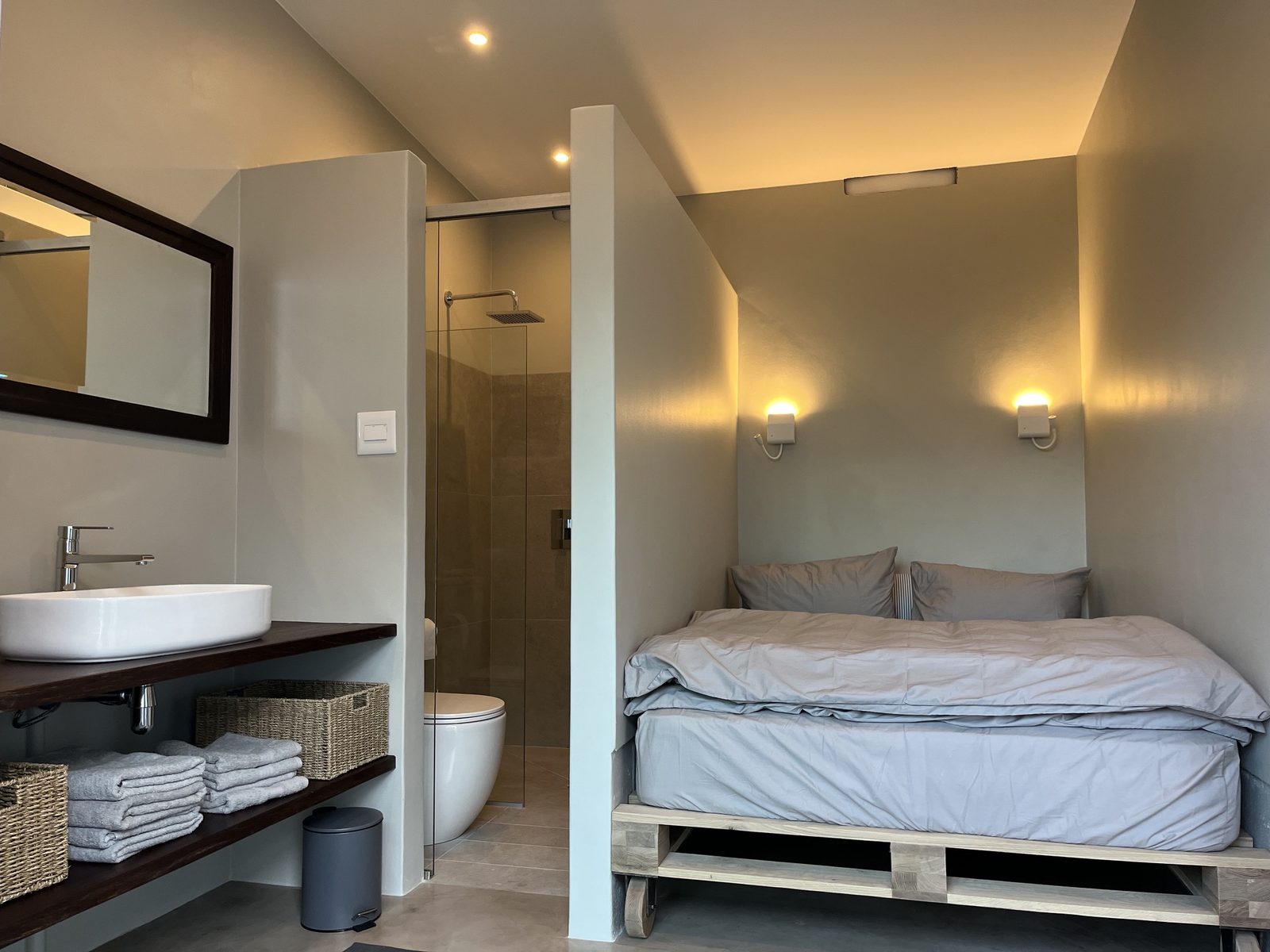 Schlafbereich mit Queensize-Bett, daneben Lavabo und Dusche